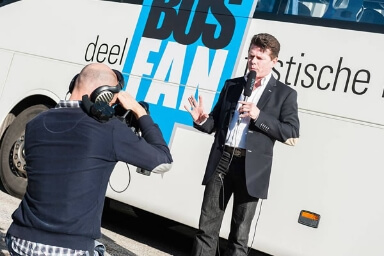 Tony est filmé devant un bus comme un présentateur de nouvelles