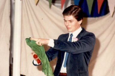 Tony fait un tour de magie avec des balles rouges et un foulard vert en tant que jeune magicien