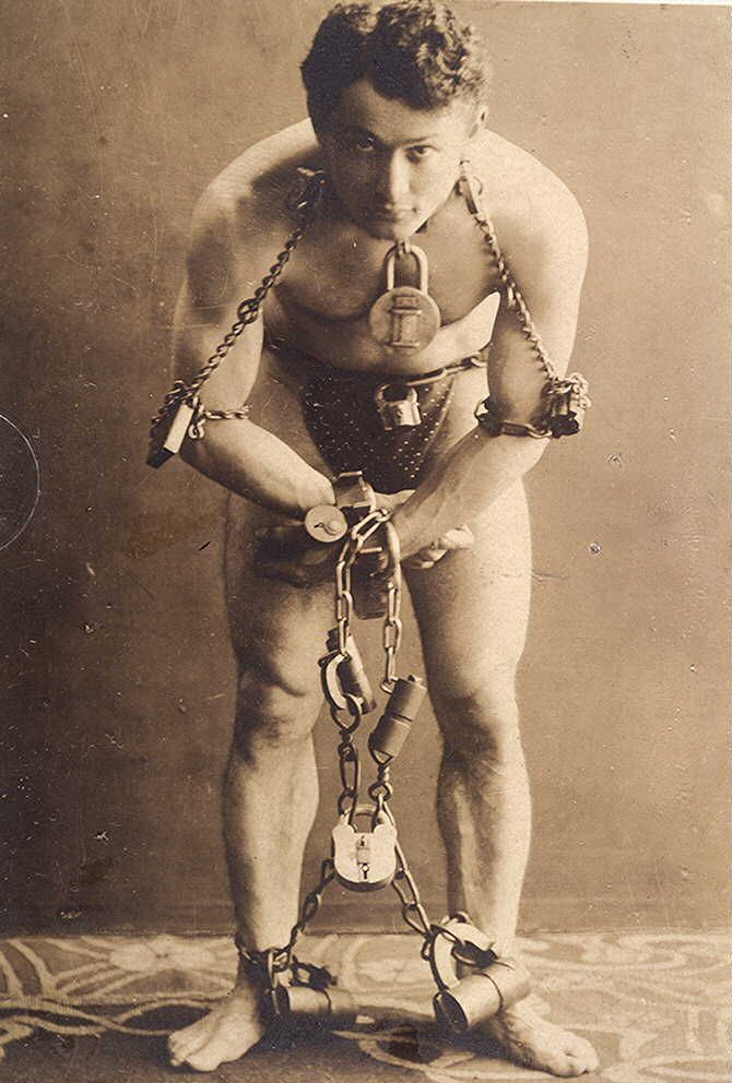 Een afbeelding van Houdini volledig in handboeien en met kettingen.