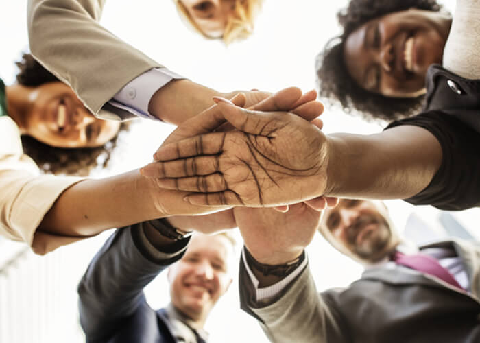 Mensen leggen de handen op elkaar tijdens een teambuildingactiviteit.